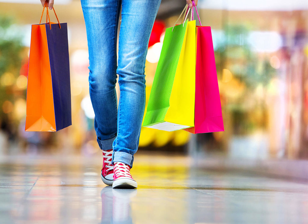 legs of a person walking with shopping bags with mall interior in the background