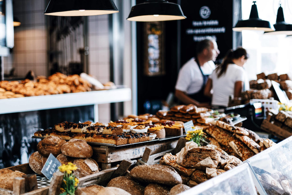 fresh baked breaks and other goods dispayed in a restaurant with two employees in the background