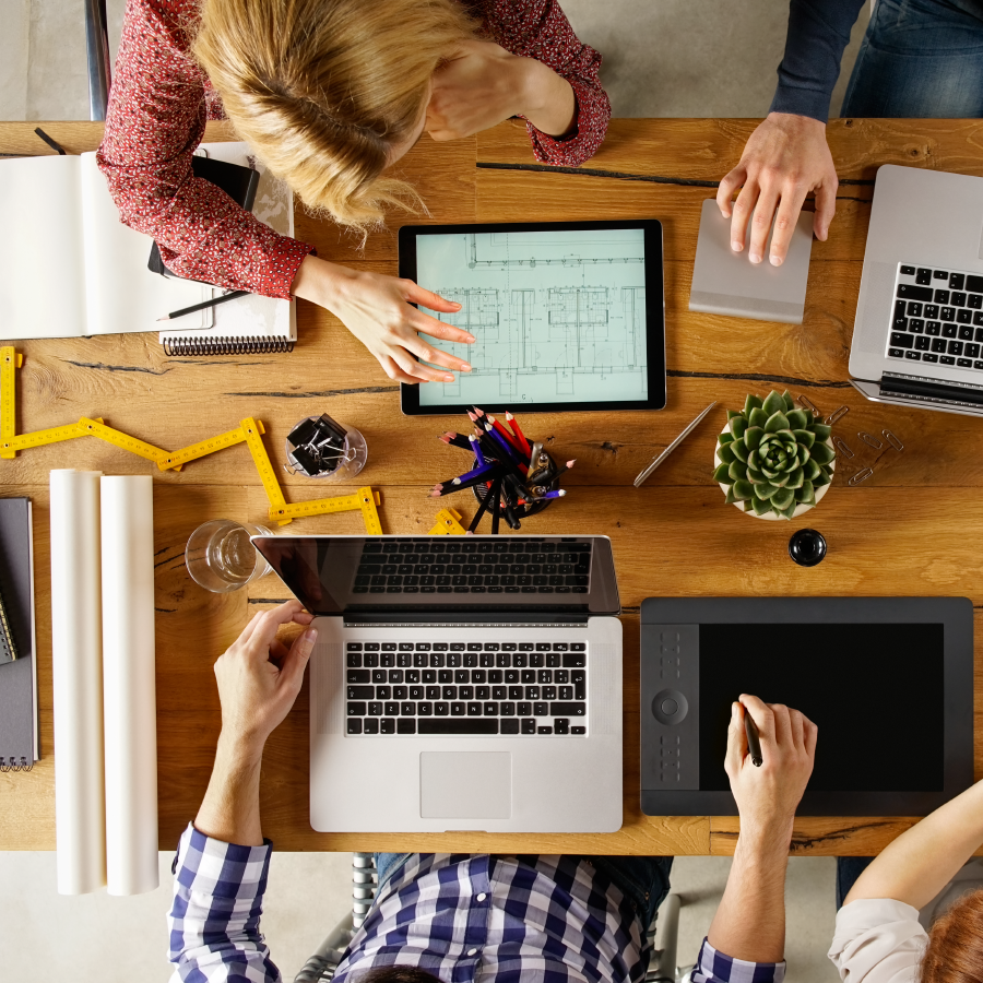 Paperless Business Processes and e-Freight in the Forwarding Sector 1 team sitting at a table collaborating with laptops, tablets, drawing tablets, and trackpad