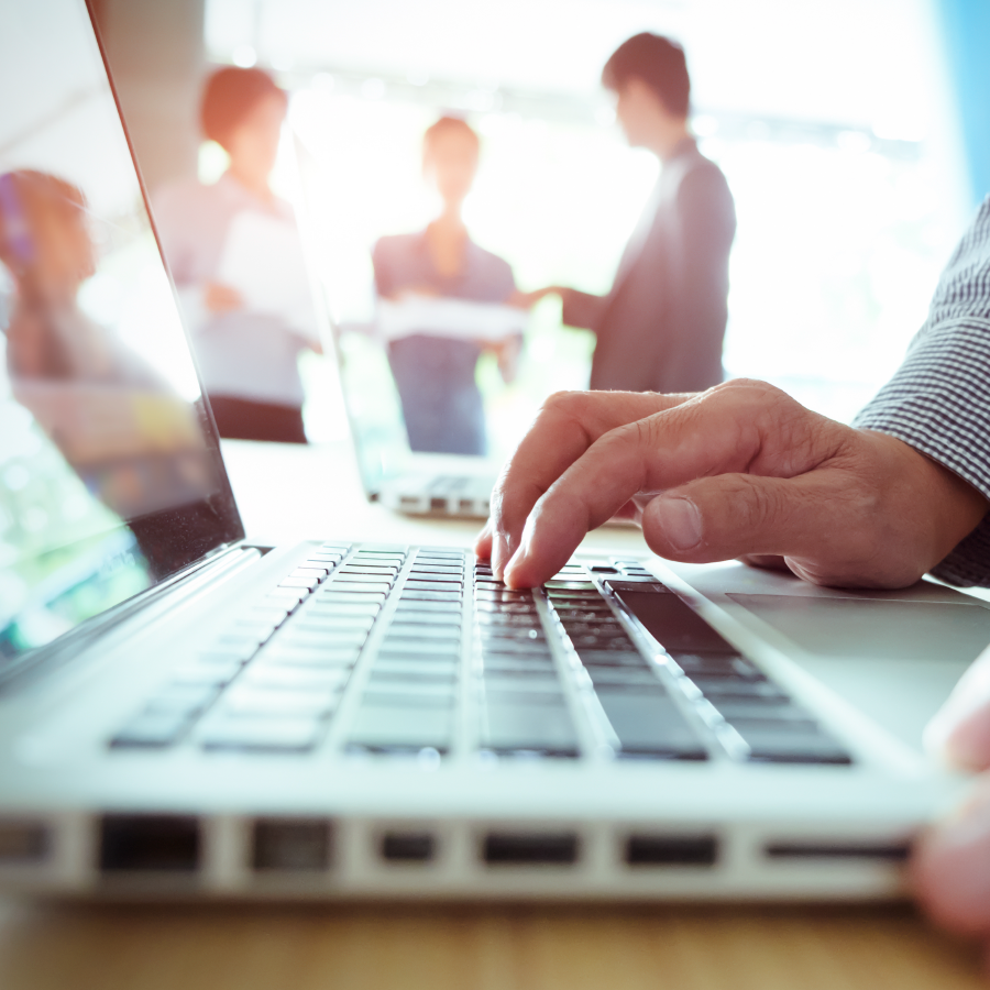 5 Reasons to Buy a True SaaS Transportation Management System 1 man typing on keyboard with other people out of focus in the background